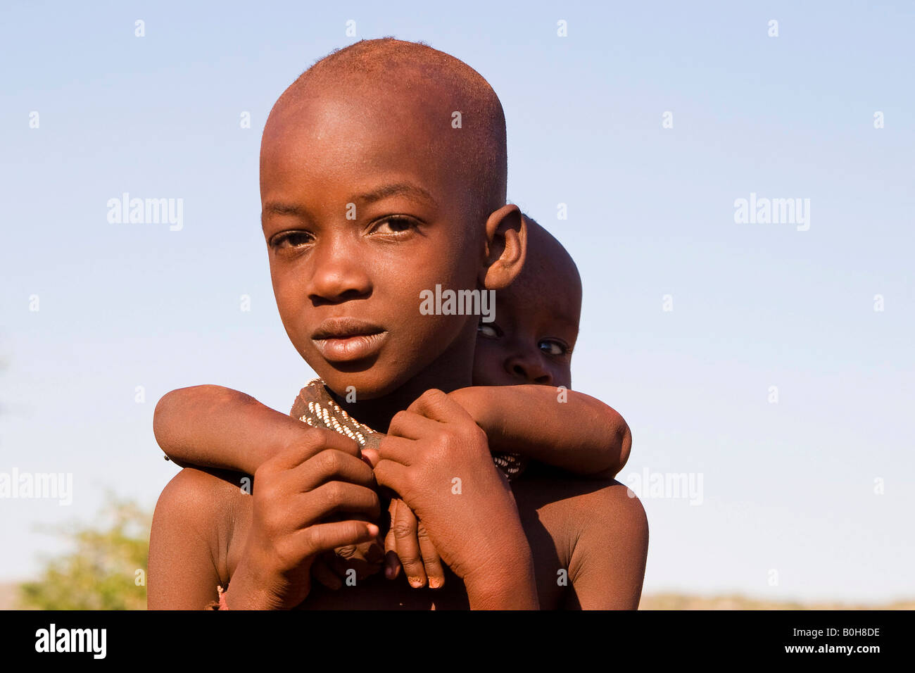 Himba boy carrying his little brother piggy-back, Namibia, Africa Stock Photo