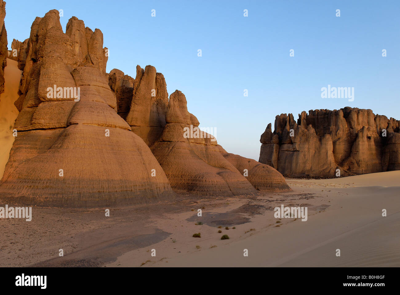 Eroded rock formations rising out of desert sand in Tin Akachaker, Tassili du Hoggar, Wilaya Tamanrasset, Algeria, North Africa Stock Photo