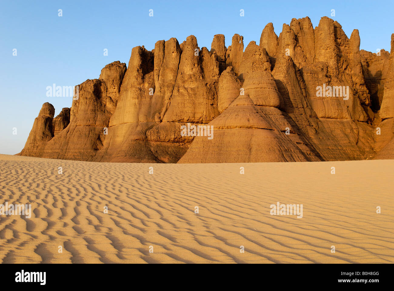 Eroded rock formations rising out of desert sand dunes, ripples in Tin Akachaker, Tassili du Hoggar, Wilaya Tamanrasset, Sahara Stock Photo