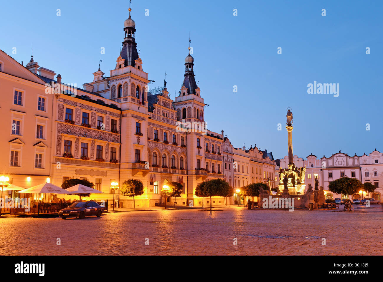 Ornate facade of buildings under streetlights at twilight surrounding the cobbled town square in the historic centre of Pardubi Stock Photo