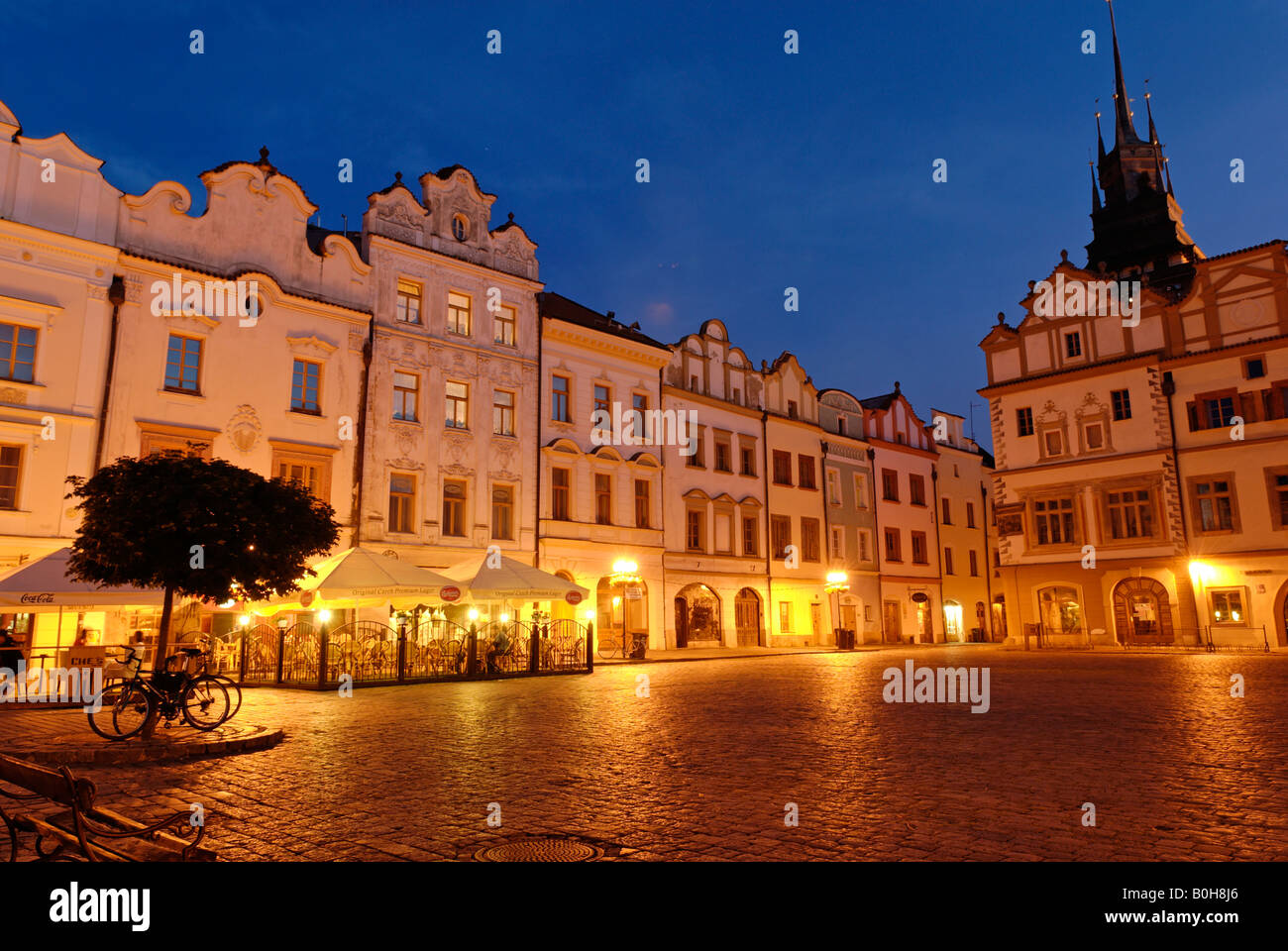 Ornate facade of buildings under streetlights at twilight surrounding the cobbled town square in the historic centre of Pardubi Stock Photo