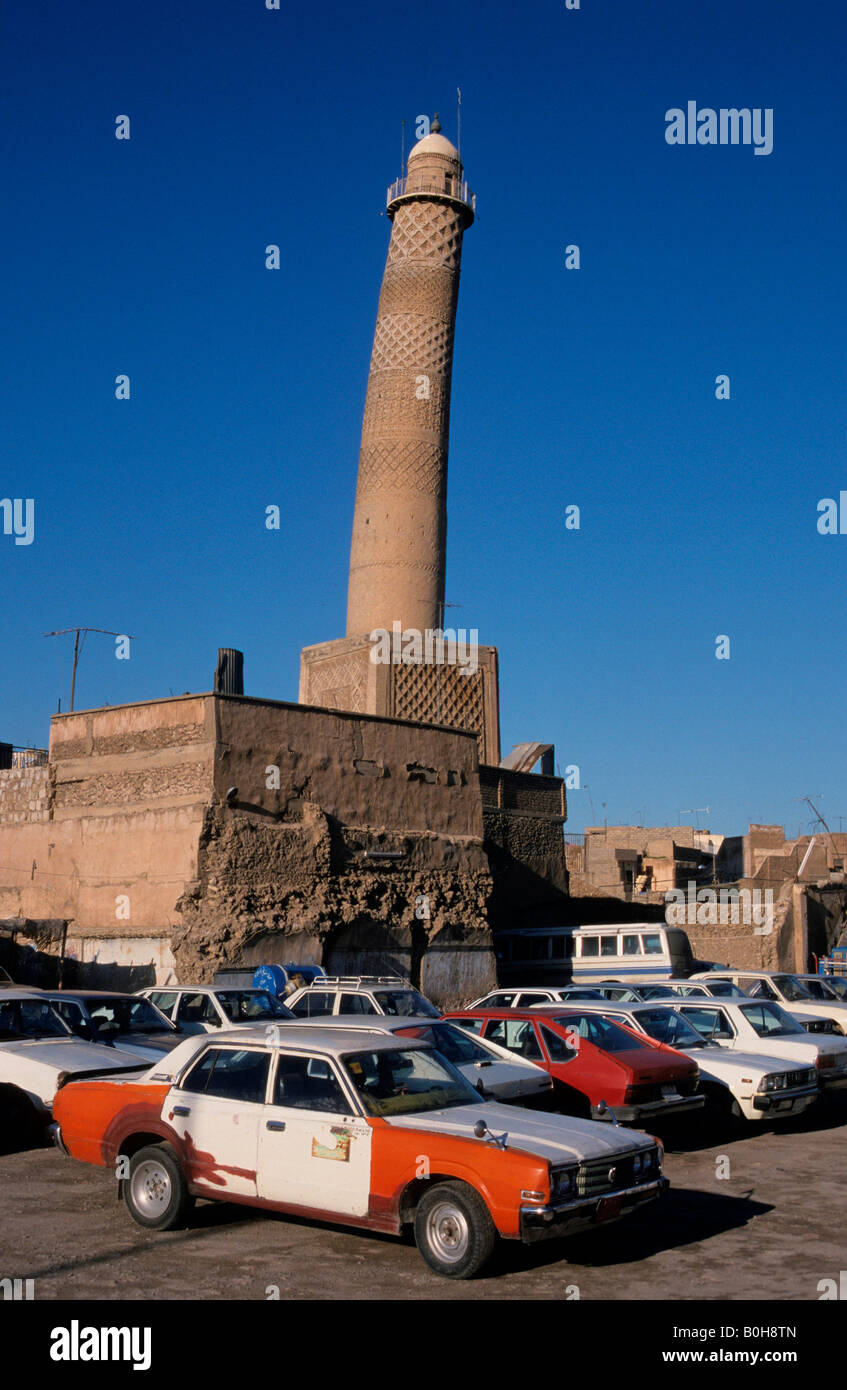 Beat up old cars parked in front of the leaning crooked minaret of the Nuriya Mosque (Jami an-Nuri, built 1148), Mosul, Iraq, M Stock Photo