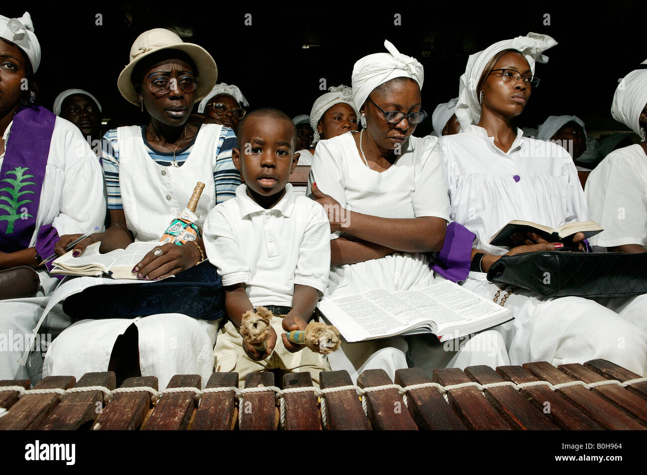 Young boy sitting between singing woman playing the marimba during a church  service in Douala, Cameroon, Africa Stock Photo - Alamy