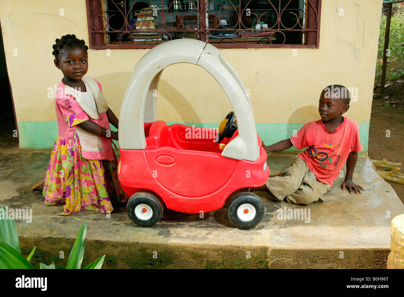 Boy and girl playing with a peddle car at an AIDS / HIV orphanage in Douala, Cameroon, Africa Stock Photo