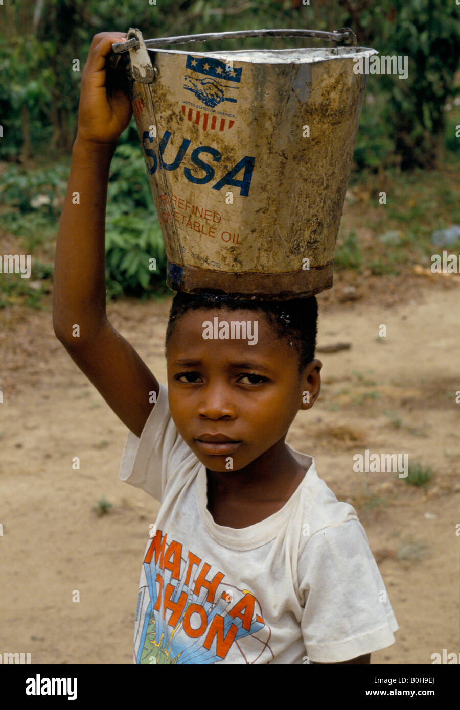 A child collecting water using a bucket of vegetable oil donated by