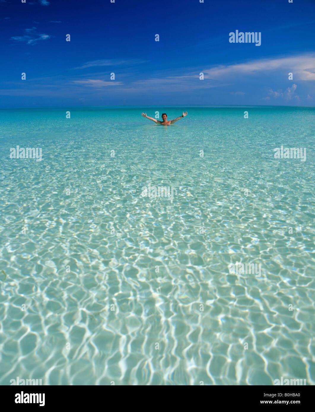 Crystal clear ocean water, man standing in shallow water, Maldives, Indian Ocean Stock Photo