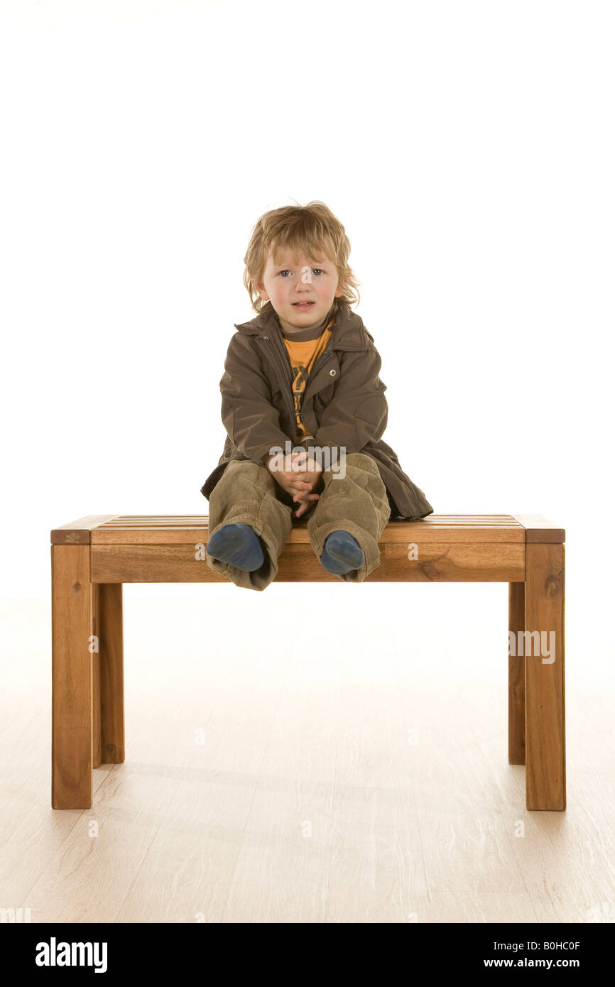 Two-year-old boy sitting on a bench Stock Photo