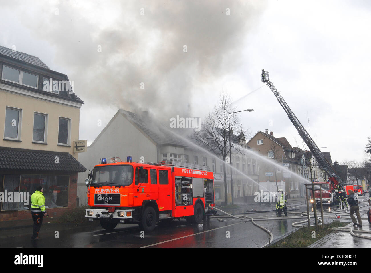 Firefighters fighting a roof fire using high pressure hoses and a mobile ladder in Bergisch Gladbach, North Rhine-Westphalia, G Stock Photo