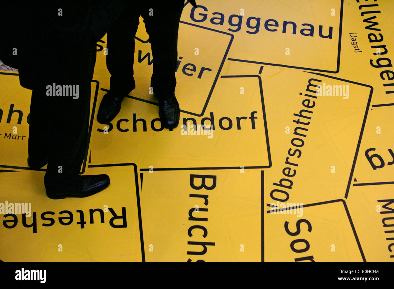 Men standing on an image of town signs of various place names in Baden-Wuerttemberg, Germany Stock Photo
