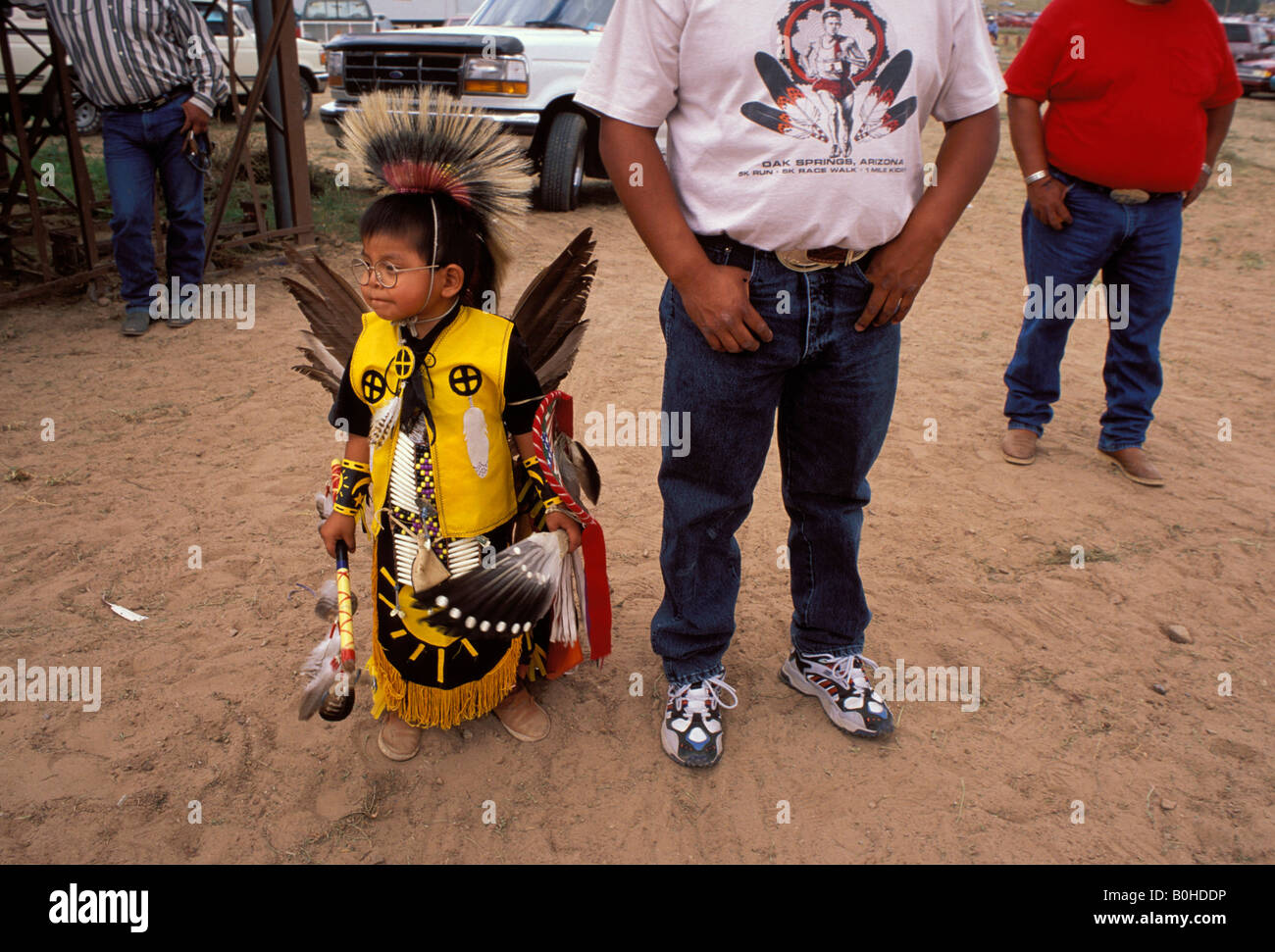 A child in traditional Navajo costume stands among Navajo men, USA
