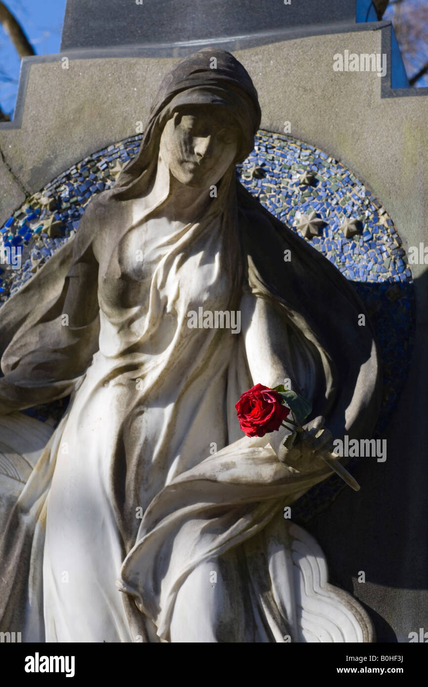 Angel statue holding red rose on a gravestone, Alter Suedfriedhof Cemetery, Munich, Bavaria, Germany Stock Photo