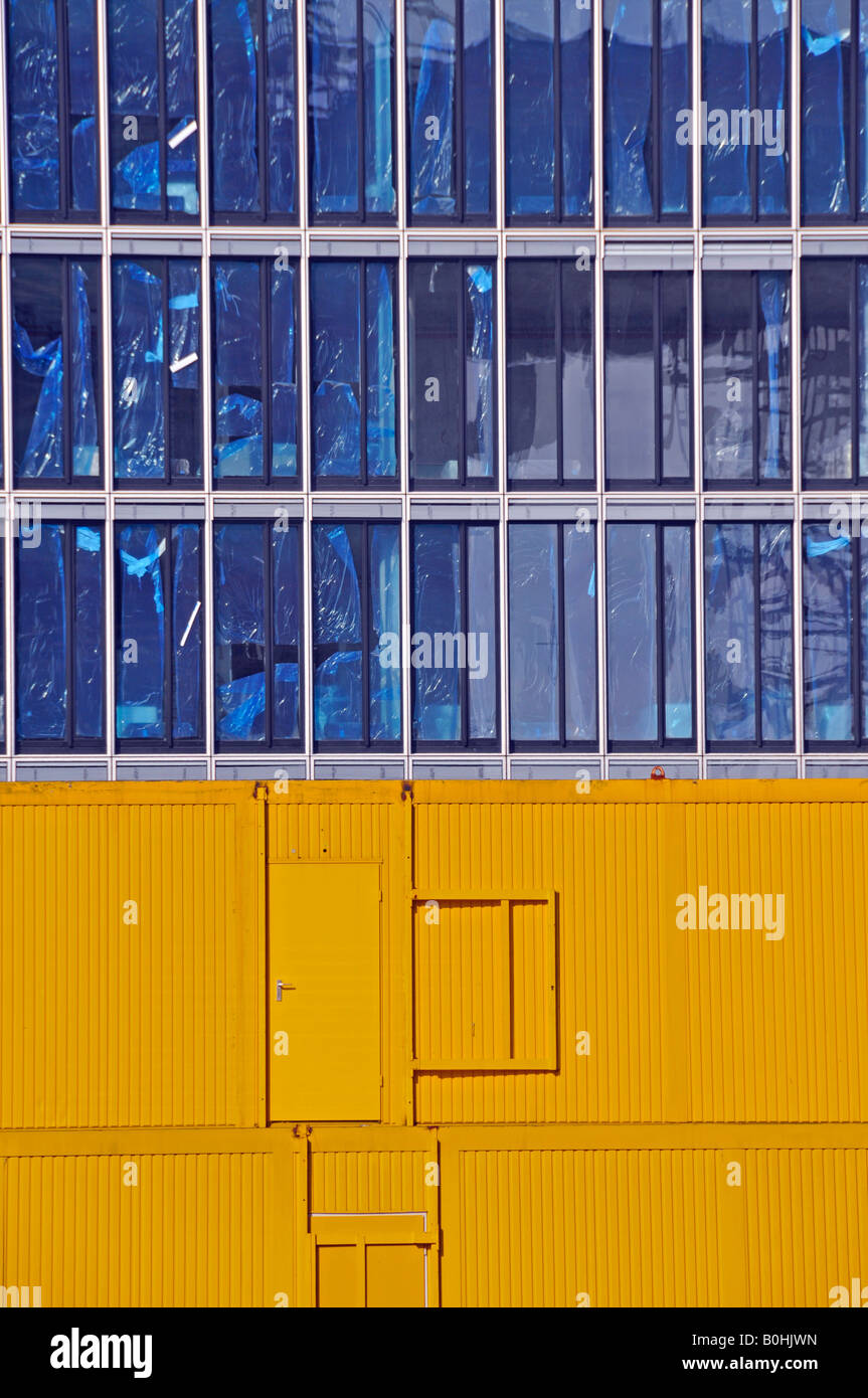 Yellow portable building site offices in front of the new Kranhaus 1 office tower, building site at Rheinauhafen Harbour in Col Stock Photo