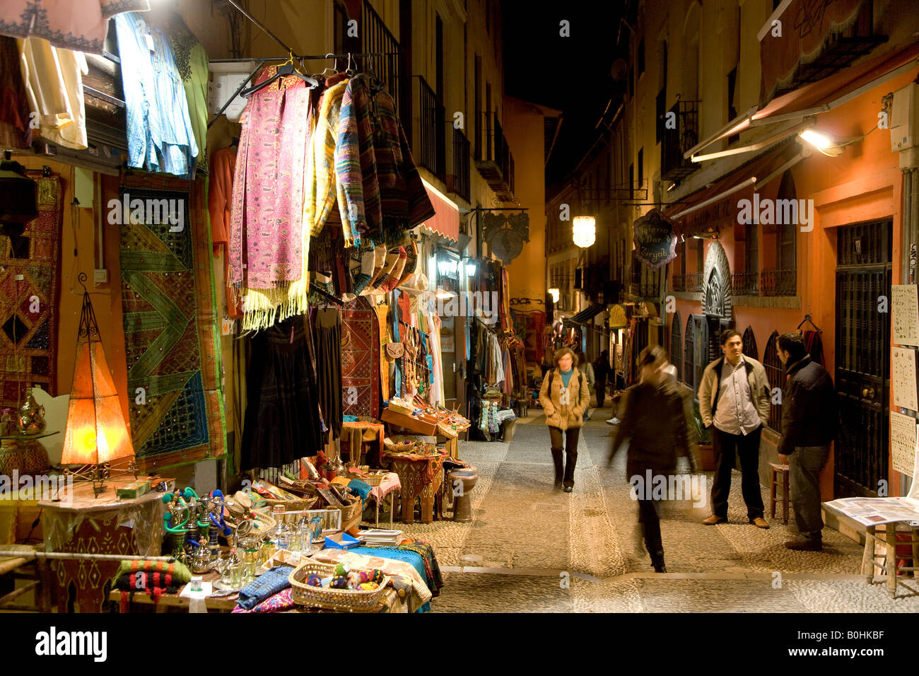 Teahouses, tourists and souvenir shops selling Moroccan handicrafts at night in the colourful Caldereria Nueva street, Granada, Stock Photo