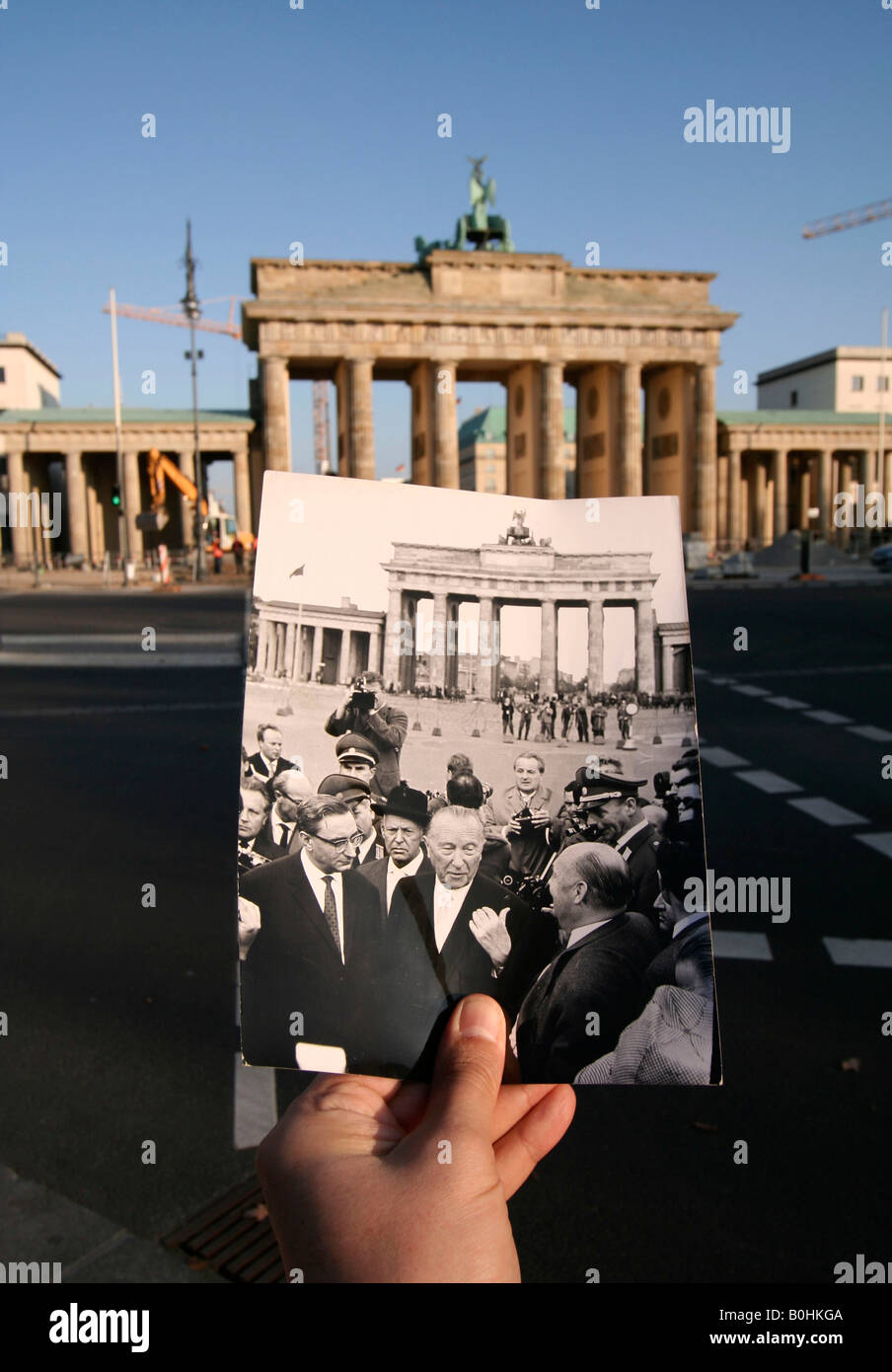 Then and now, hand holding a black and white photo of Konrad Adenauer in front of the Brandenburger Tor or Brandenburg Gate, Be Stock Photo