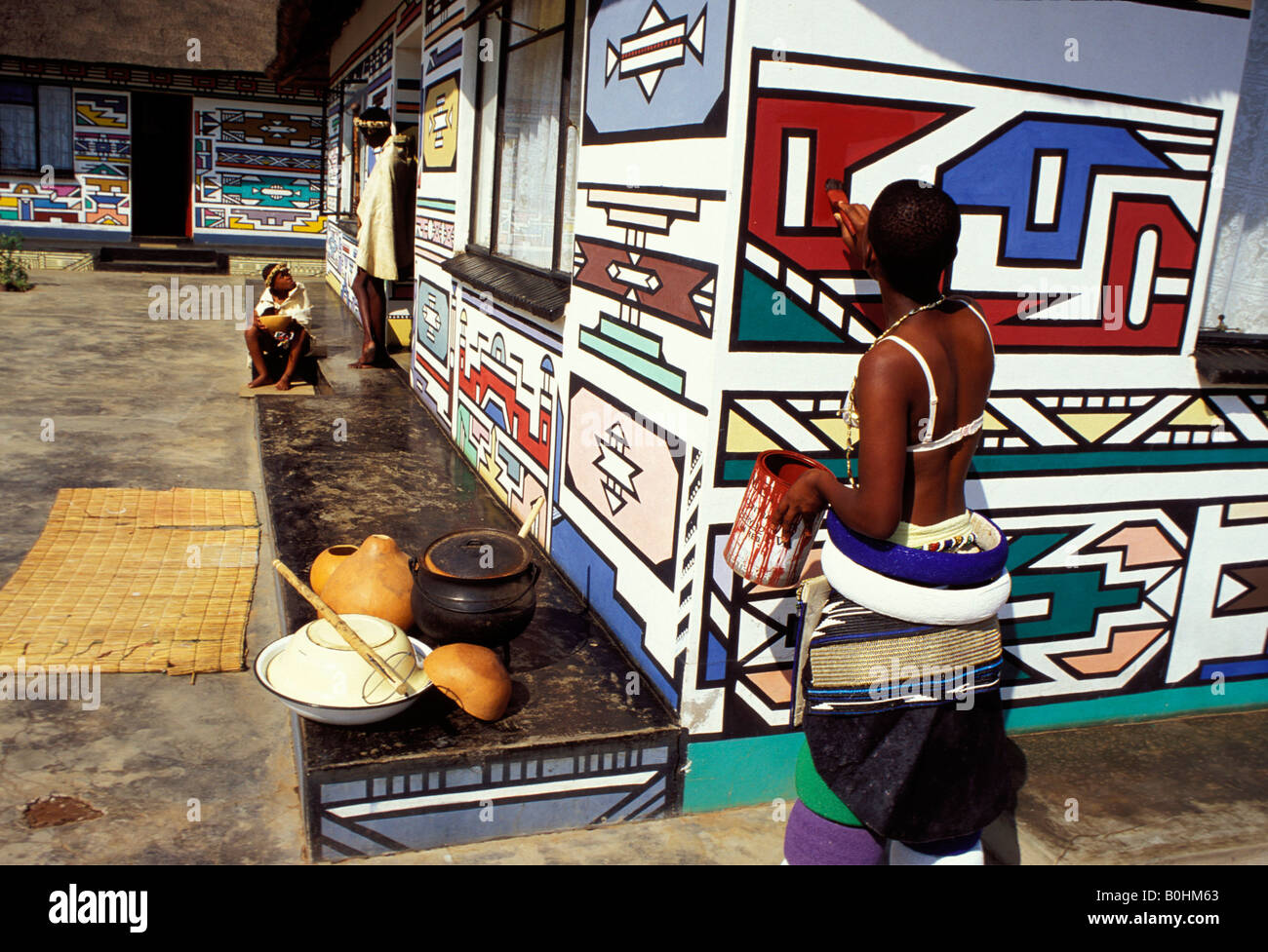 A Ndebele woman painting a wall, South Africa. Stock Photo