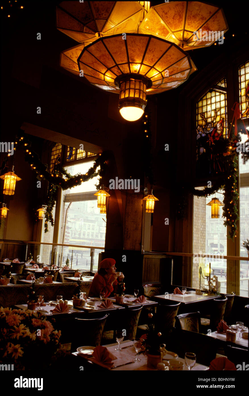 A woman sitting alone in the restaurant of the American Hotel, Amsterdam, Netherlands. Stock Photo