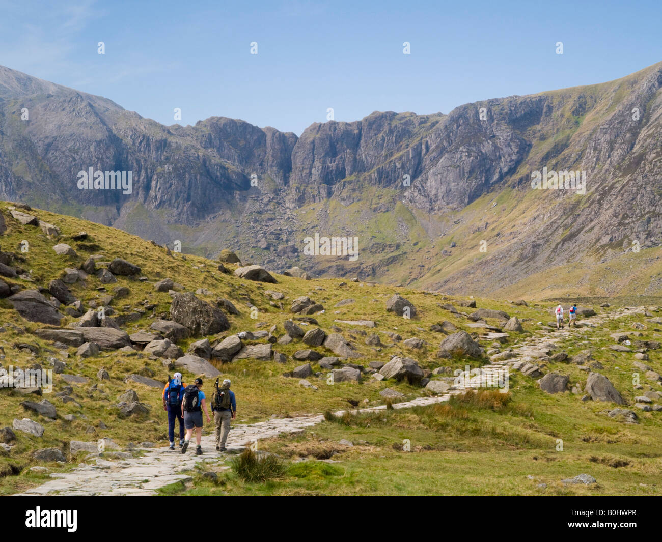 Hikers hiking on footpath to Cwm Idwal with Devil's Kitchen (Twll Du) beyond in Snowdonia National Park, Ogwen, North Wales, UK Stock Photo