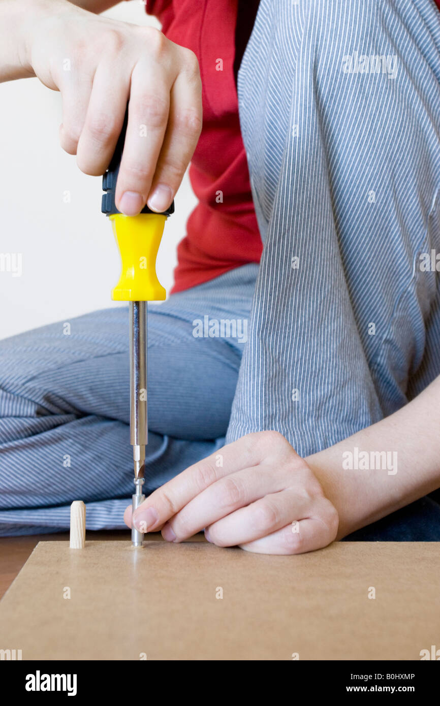 A woman screwing a screw into the underside of a desk Stock Photo Alamy
