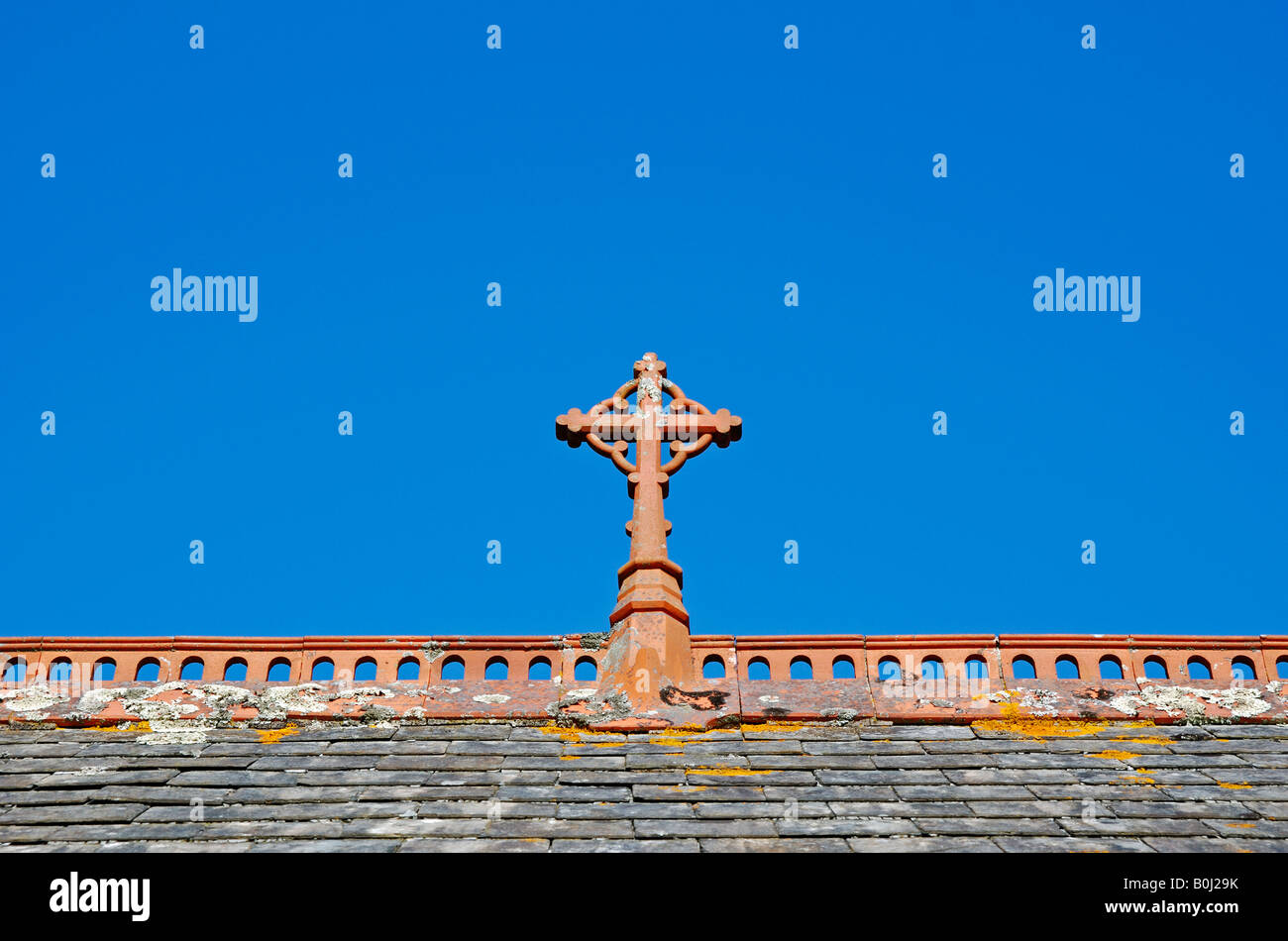 a christian cross on the ridge of a church roof Stock Photo