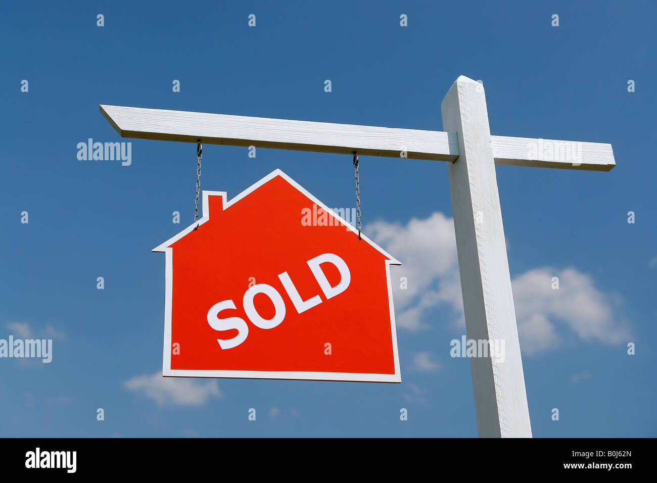White wooden post with red house Sold notice board over blue sky Stock Photo