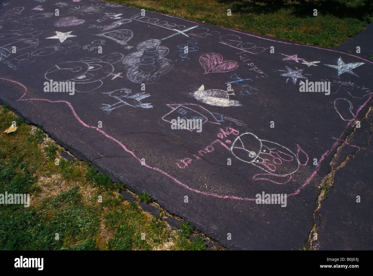 childrens chalk art work graffiti on suburban home asphalt driveway