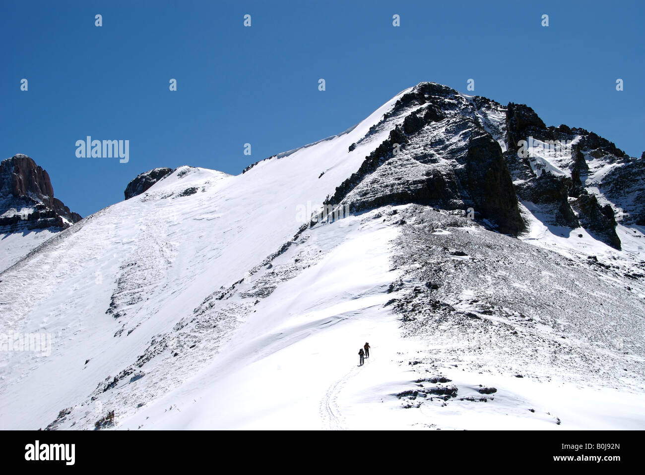 two backcountry skiers climb a mountain to ski down it high up in the San Juan mountains, Colorado. Stock Photo