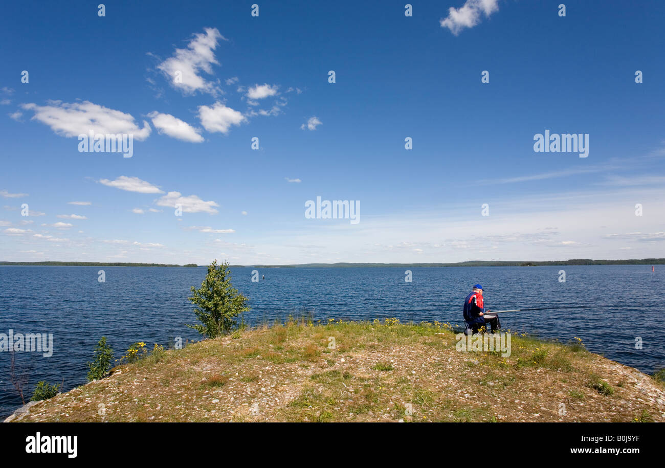 Senior male angling at Summer at lake shore, Finland Stock Photo