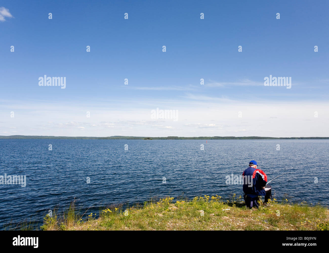Angler at lake shore, Finland Stock Photo