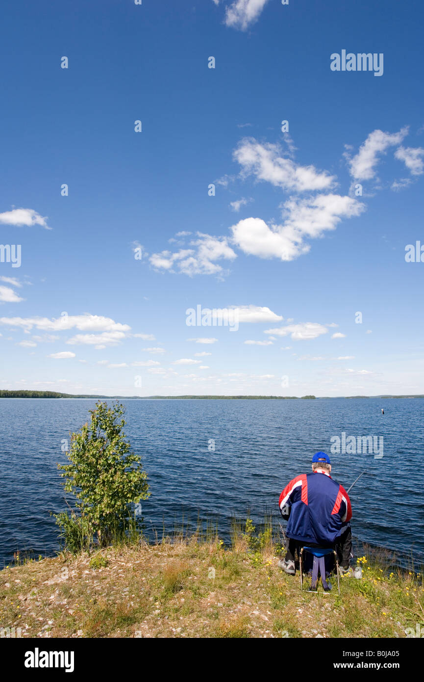 Angler at lake shore, Finland Stock Photo