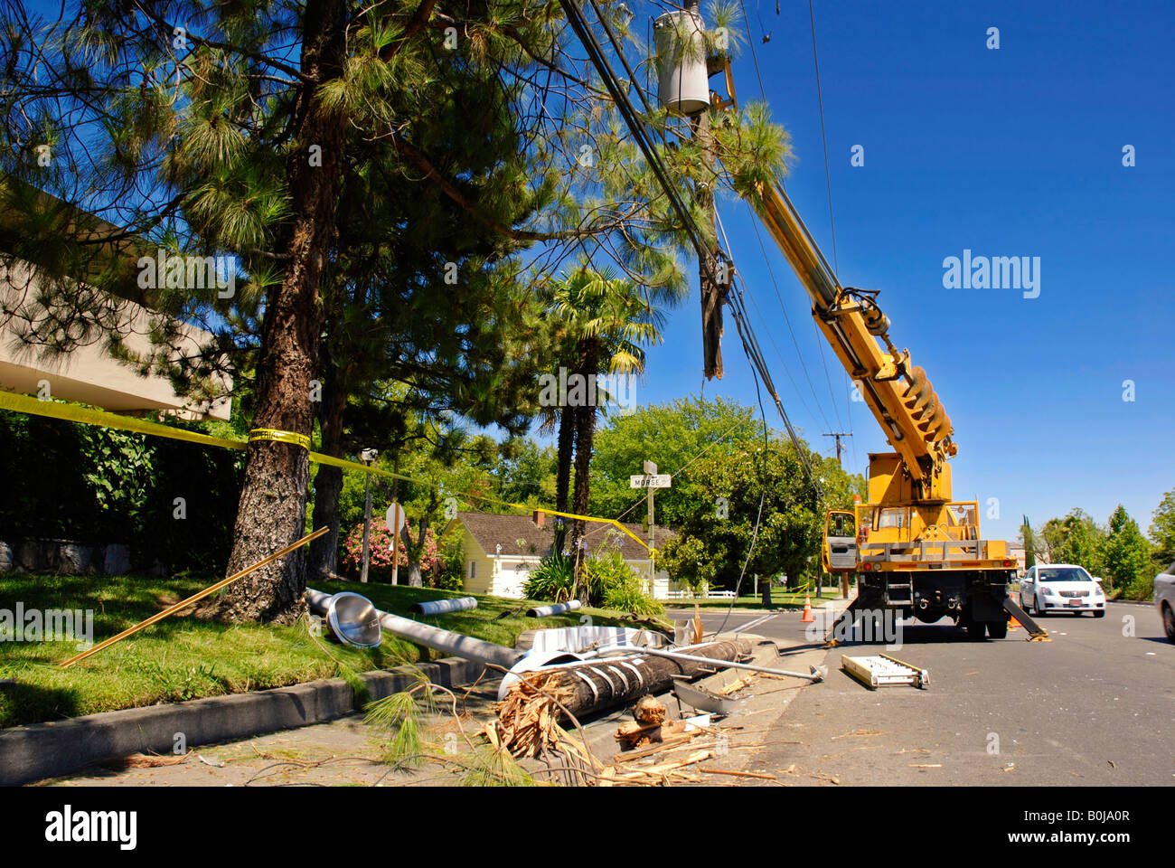 Utility truck lifts a severed power pole and lines after an accident