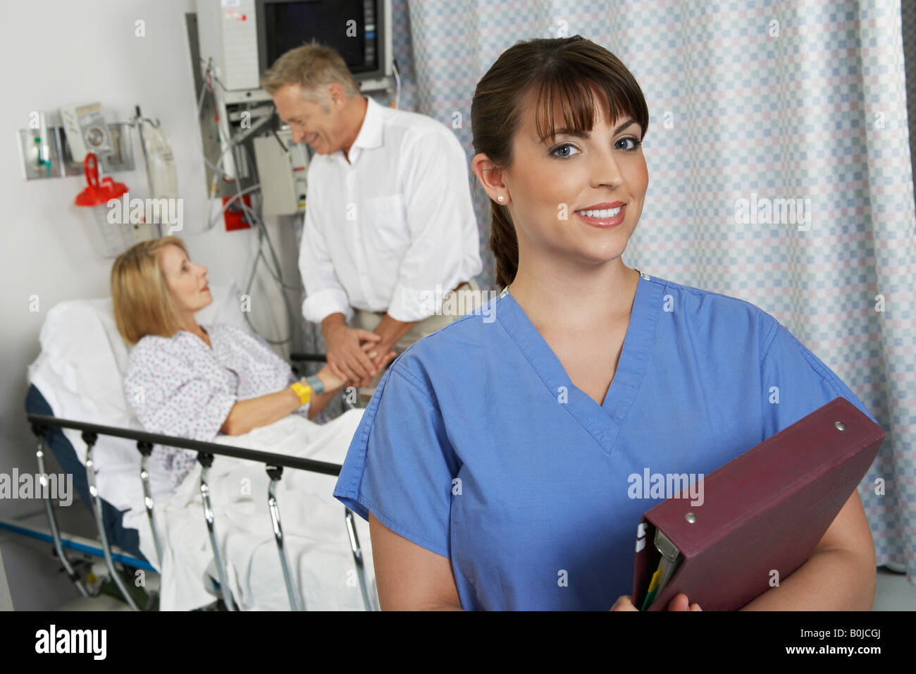 Portrait of female nurse in hospital room, patient in background Stock ...