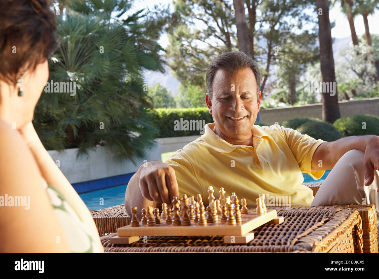 Man and woman playing chess by swimming pool Stock Photo Alamy
