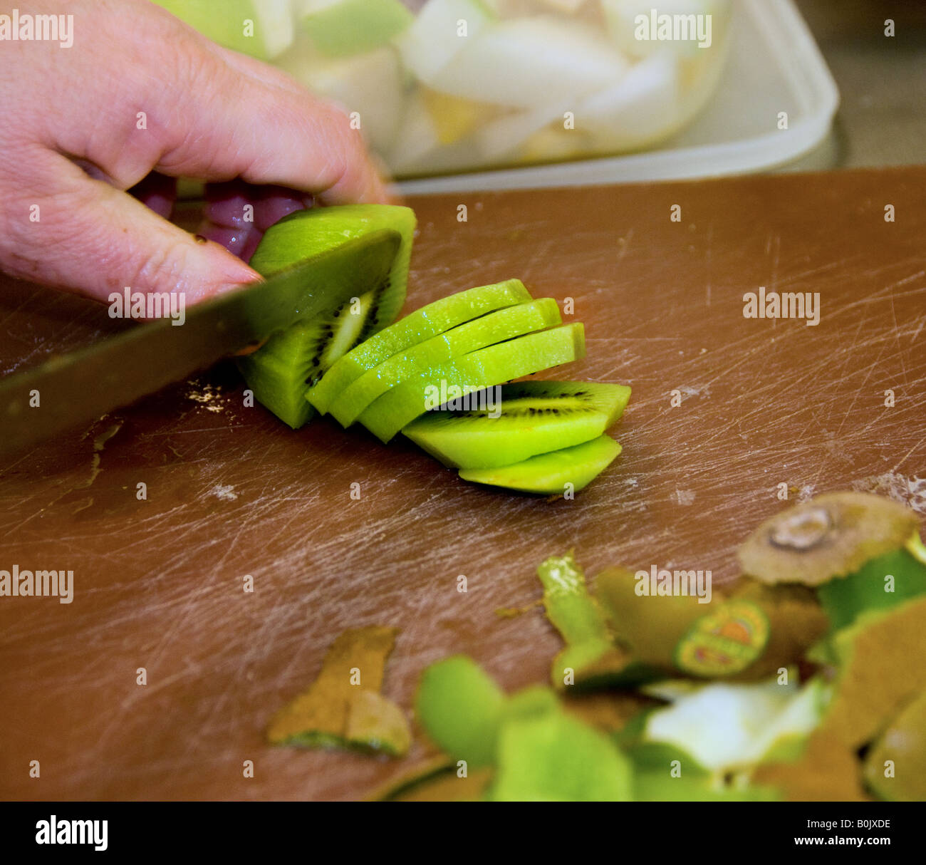 Food preparation - A kiwifruit being sliced. Stock Photo