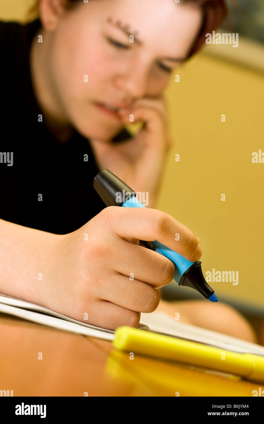 A pensive redhead student girl marking notes with a blue marker and biting her nails Stock Photo