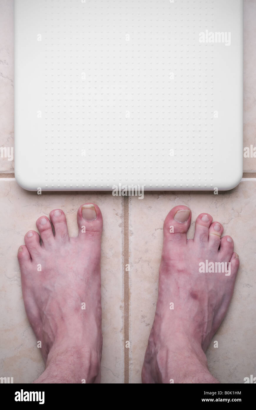 Ugly feet getting ready to step on a bathroom scale Stock Photo