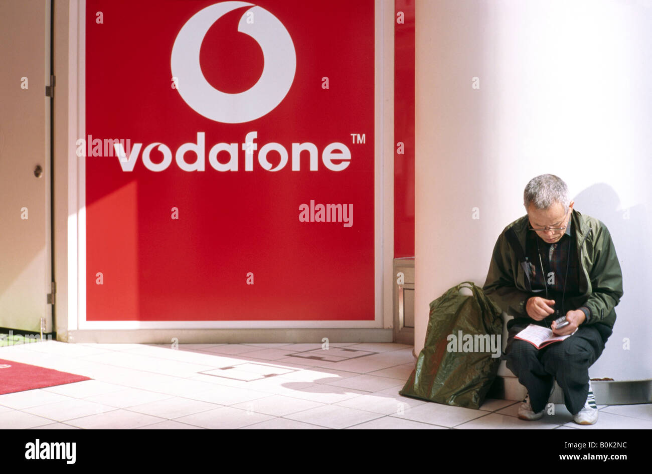 Nov 2, 2004 - Man checking his mobile phone outside Shibuya's Vodafone store (now Softbank Mobile) in central Tokyo. Stock Photo