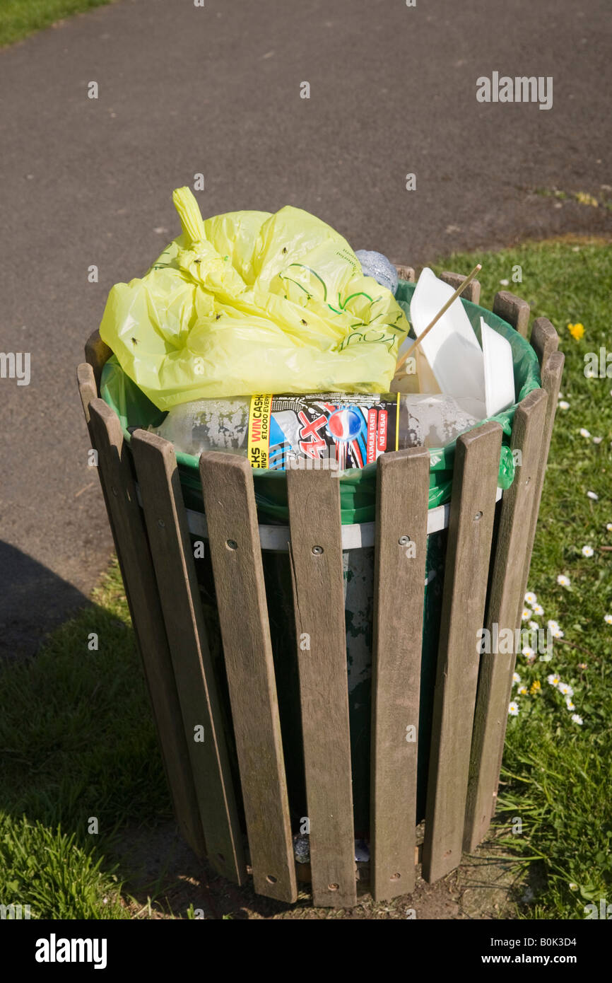 Litter bin containing plastic bag bottle and polystyrene rubbish covered in flies UK Stock Photo