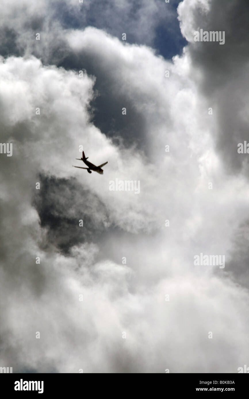 plane flying through dark clouds in sky Stock Photo - Alamy