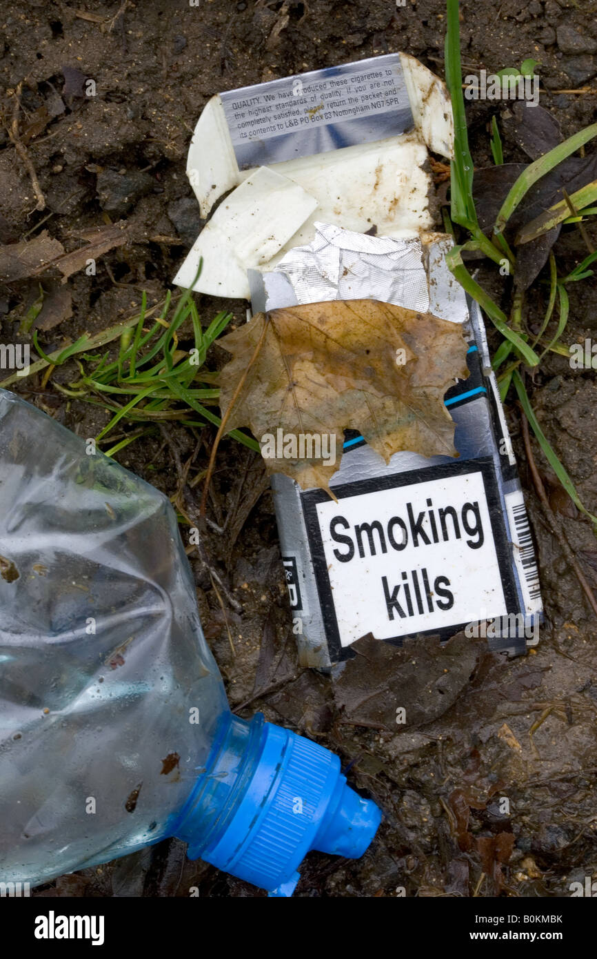 Cigarette packet showing SMOKING KILLS and plastic bottle discarded by