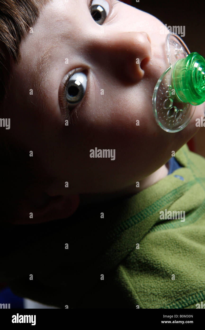 A three years old boy with a pacifier dummy in his mouth Stock Photo