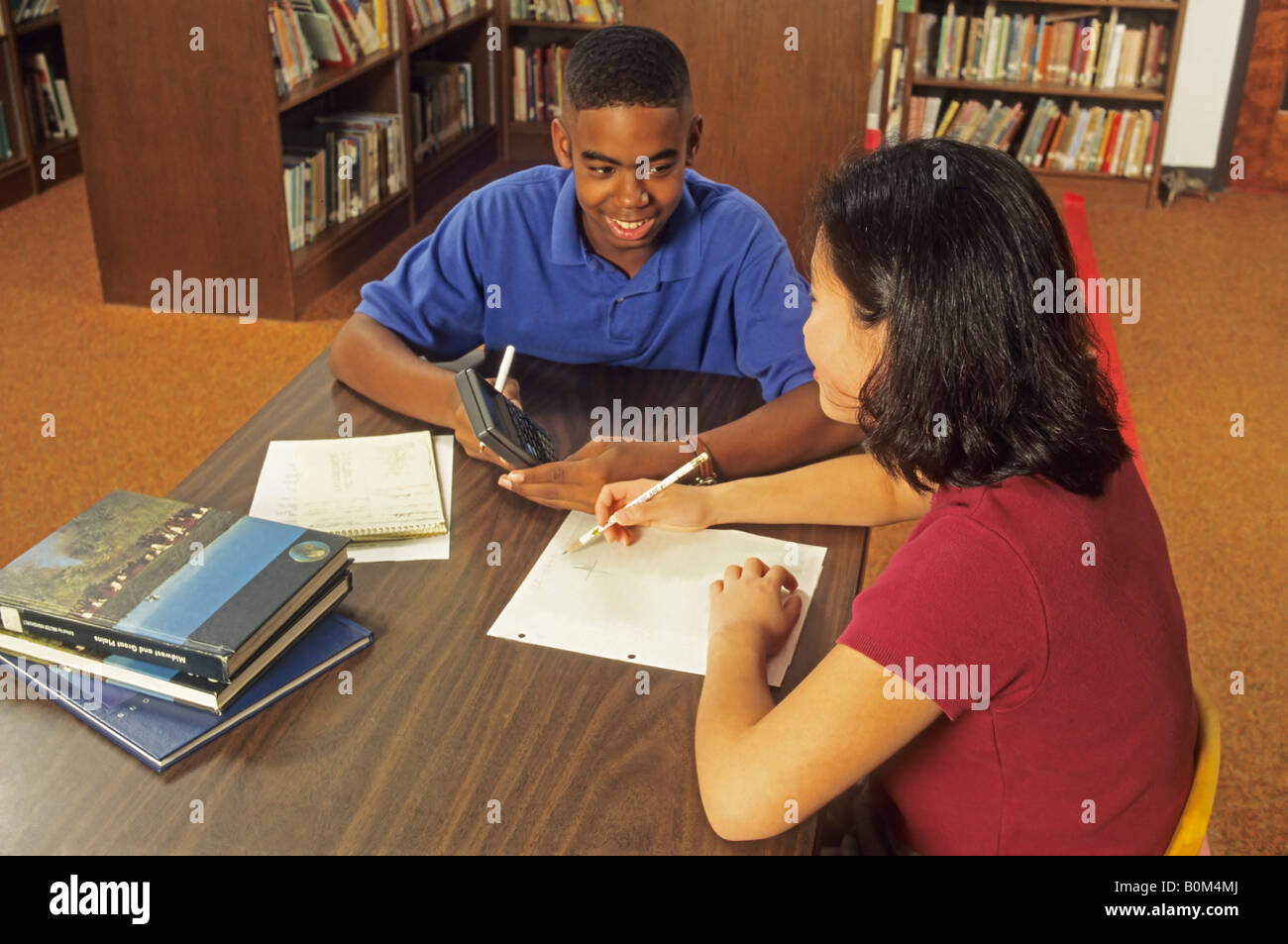 Teen students doing math homework in library, graphing calculator for equations, ethnic mix Ohio USA Stock Photo
