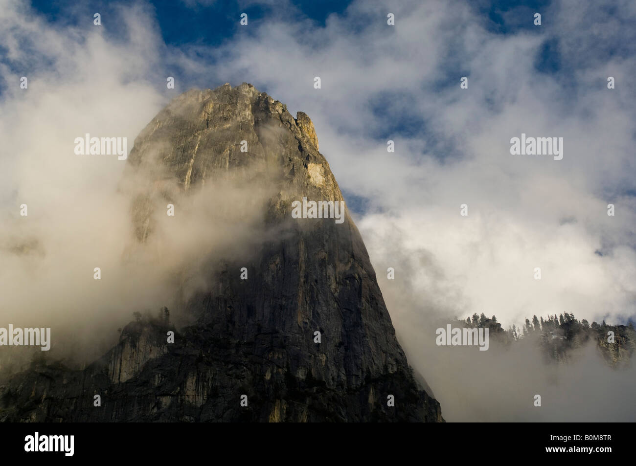 Storm clouds shroud the sheer granite cliff of Sentinel Rock at sunset