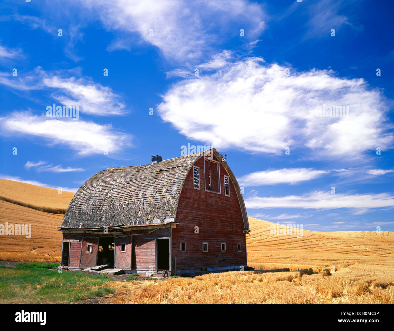 Whitman County WA Weathered red barn adjacent to a field of harvested wheat under a summer sky Stock Photo