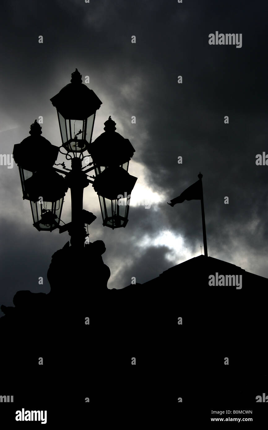 City of Westminster, England. Silhouetted close up view of Buckingham Palace east façade gate lamps and flagstaff. Stock Photo