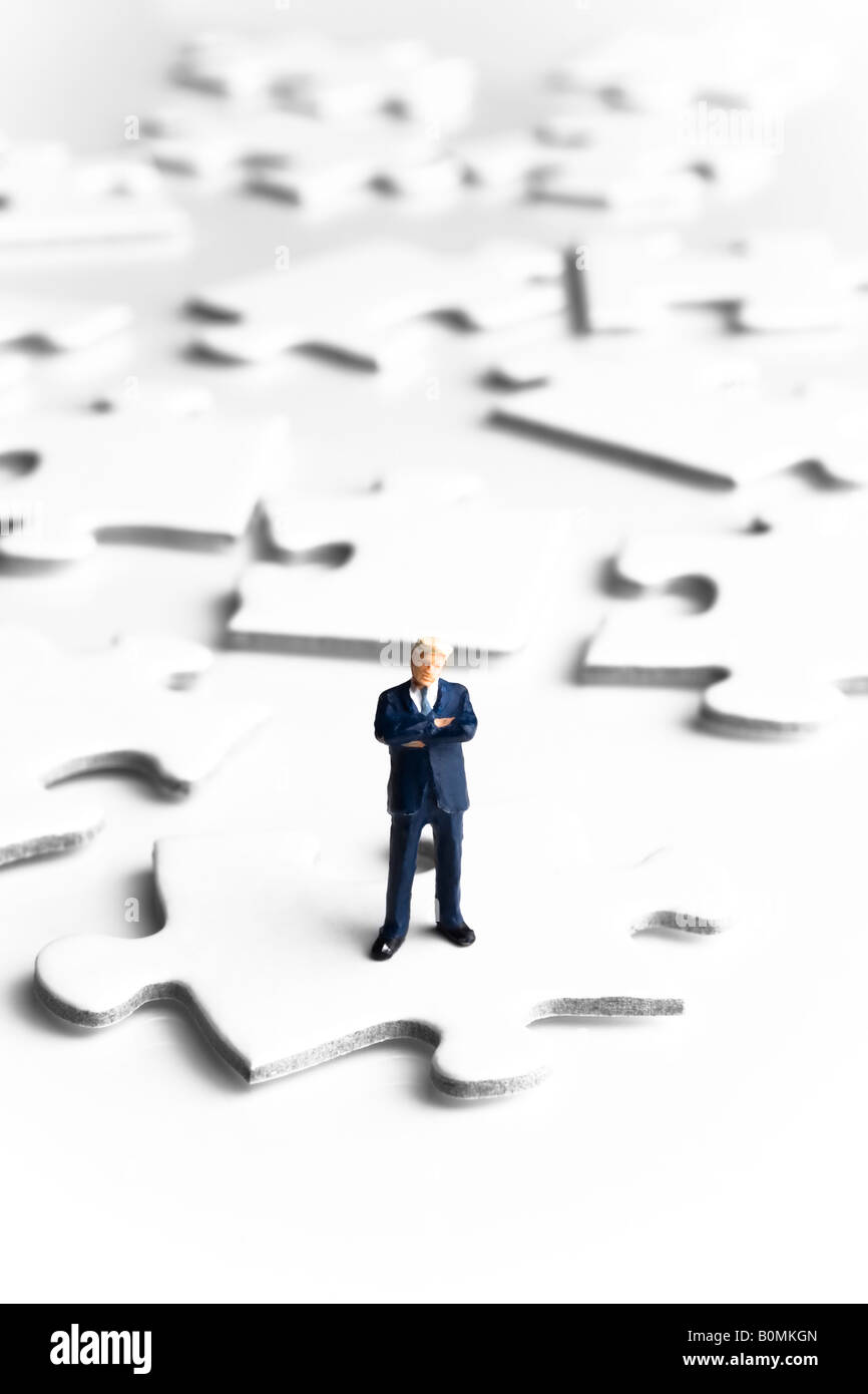 Businessman figurine standing on a puzzle piece Stock Photo