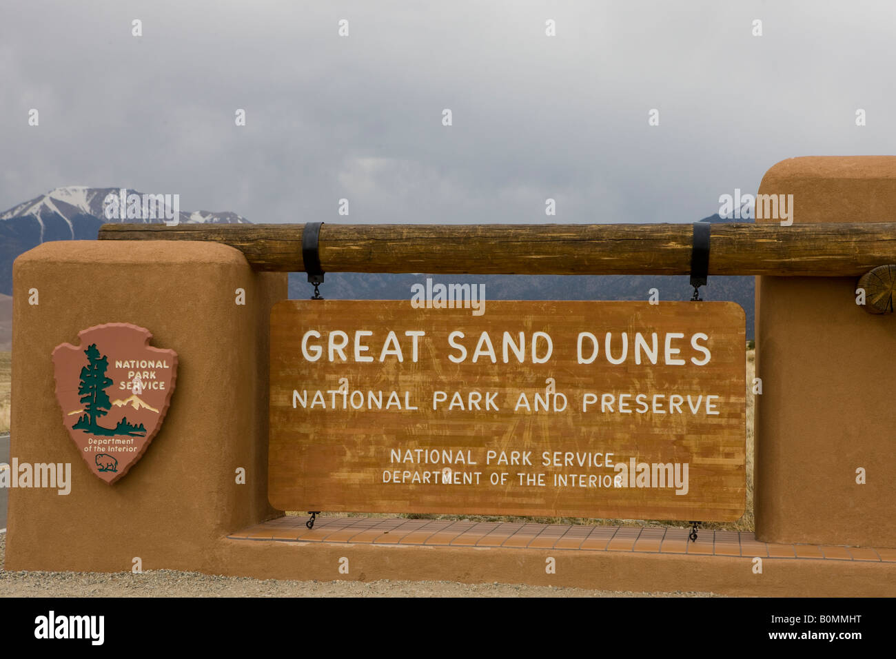 Welcome sign to Great Sand Dunes National Park and Preserve with snow capped Sangre de Christo mountains in the background CO US Stock Photo