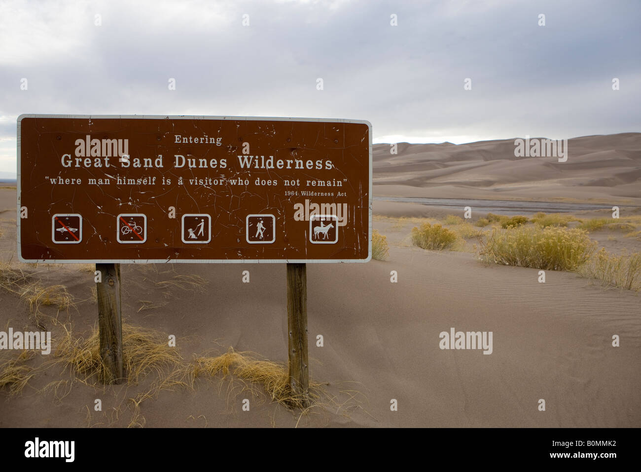 Sign at entrance to dune field which reads Entering Great Sand Dunes Wilderness where man himself is a visitor who does remain Stock Photo