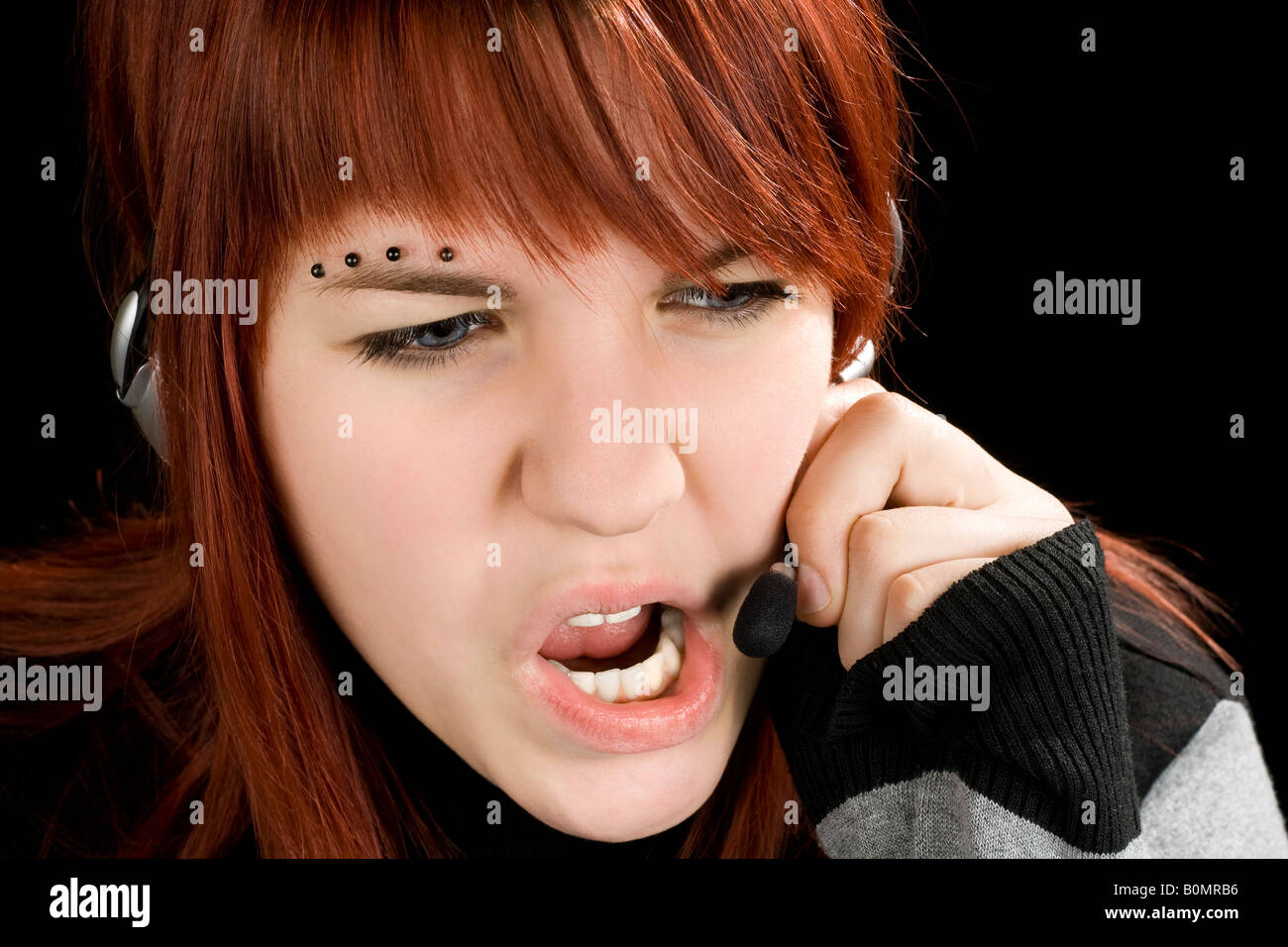 A redhead girl swearing on the microphone talking to a customer or being unpolite and stressed Studio shot Stock Photo