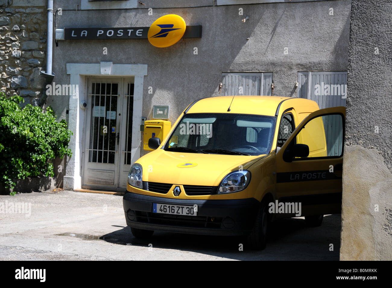 A typical yellow La Poste van outside of the rural post office in Lussan, Grad, France. Stock Photo