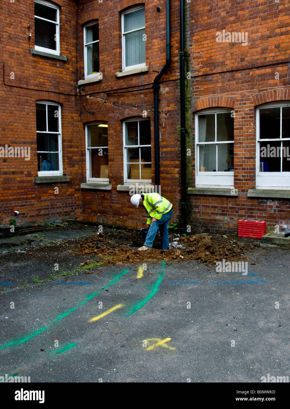 Construction work - Construction worker in hard hat and hi viz jacket digging a hole in the ground. Stock Photo
